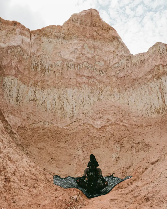 Black outfit meditating against rock wall