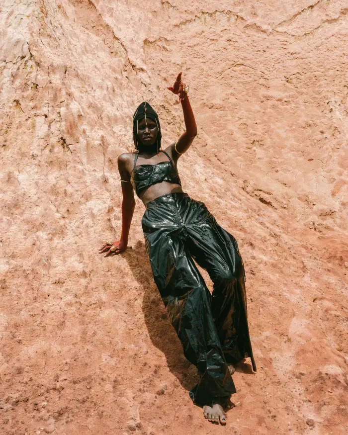 Black shiny outfit pointing up against rock